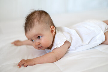 Caucasian baby girl as he lays on a fluffy down duvet comforter on a bed