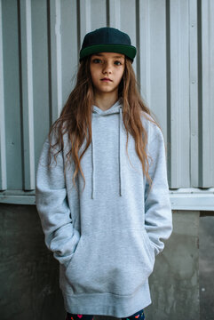 City portrait of handsome girl kid wearing gray blank hoodie or sweatshirt and cap with space for your logo or design. Mockup for print
