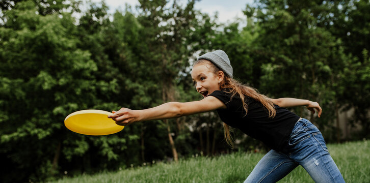 Little girl playing frisbee in the park. Summer time