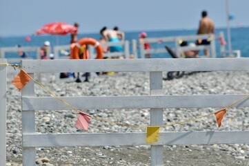 White wooden fence with colorful flags on the beach.