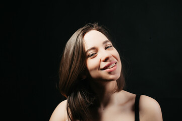 beautiful model portrait of a girl with dark hair and a black T-shirt on a black background