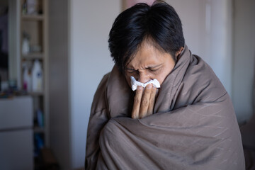 Young man with a cold blowing her runny nose with tissue. Asian man get sick sneezing from flu....