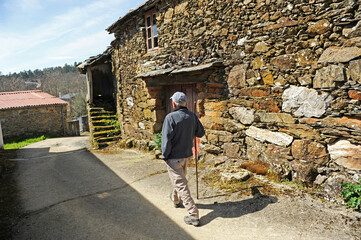 Obraz na płótnie Canvas Older man walking through the village of As Eiras on the Camino de Santiago towards Laza, Orense province, Spain