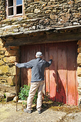 Obraz na płótnie Canvas Man knocking on the door of a house in the village of As Eiras on the Camino de Santiago to Laza, Orense province, Spain
