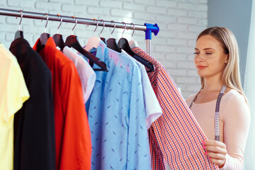 Woman tailor checking .finished clothes in her office