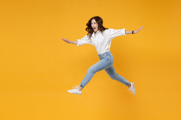 Side view excited young brunette business woman in white shirt posing isolated on yellow background. Achievement career wealth business concept. Mock up copy space. Jumping, spreading hands and legs.