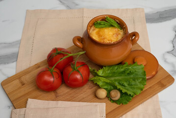 Casserole with mushrooms and cheese in the pot on the table. Julienne with chicken and mushrooms.
