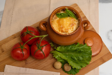 Casserole with mushrooms and cheese in the pot on the table. Julienne with chicken and mushrooms.
