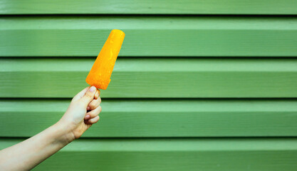 Ice cream in hand, yellow fruit ice hot summer concept