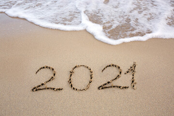 Year 2021 written at the caribbean sand beach with sea wave .