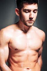 Fototapeta premium Dramatic closeup portrait of handsome young male athlete having rest after sports exercises isolated on black background