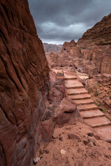 stairs path in The ancient Nabatean  city of  Petra in Jordan, with view to a main road in street of facades among sandy mountains in the desert in stormy weather