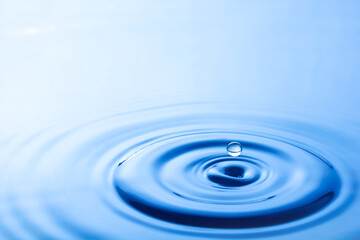 Water droplet falling impact with water surface. causing rings on water surface.