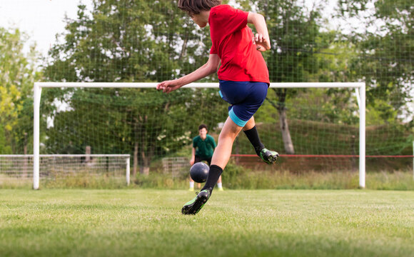 Soccer player kicks ball in a field