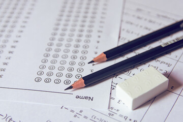 Pencil and eraser on answer sheets or Standardized test form with answers bubbled. multiple choice answer sheet