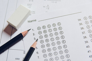 Pencil and eraser on answer sheets or Standardized test form with answers bubbled. multiple choice answer sheet