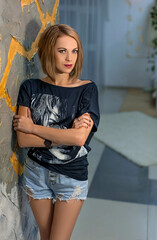 Fototapeta premium slim girl in shorts and a t-shirt with a suitcase. Mysterious traveler