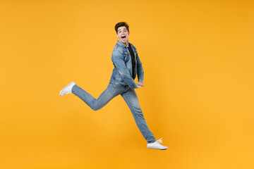 Fototapeta na wymiar Funny young man guy wearing casual denim clothes posing isolated on yellow background studio portrait. People emotions lifestyle concept. Mock up copy space. Jumping like dancing, spreading legs.