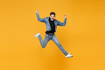 Fototapeta na wymiar Excited young man guy wearing casual denim clothes posing isolated on yellow background studio portrait. People sincere emotions lifestyle concept. Mock up copy space. Jumping, doing winner gesture.
