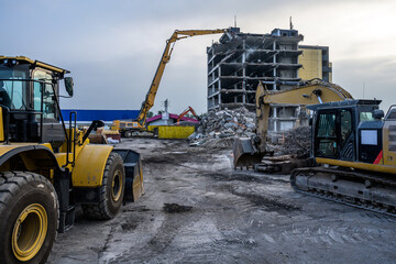 Dawn time Building House Demolition site Excavator with hydraulic crasher machine and yellow container