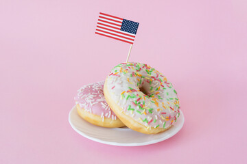 Miniature american flag stuck in donuts on pink background. 4th of july, happy usa independence day. Celebration memorial day in America.