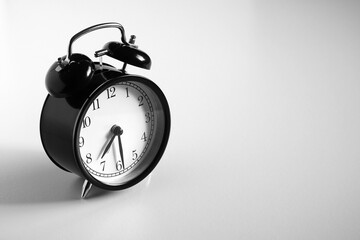 Black vintage alarm clock on table. White background. Wake up concept. An image of a retro clock...