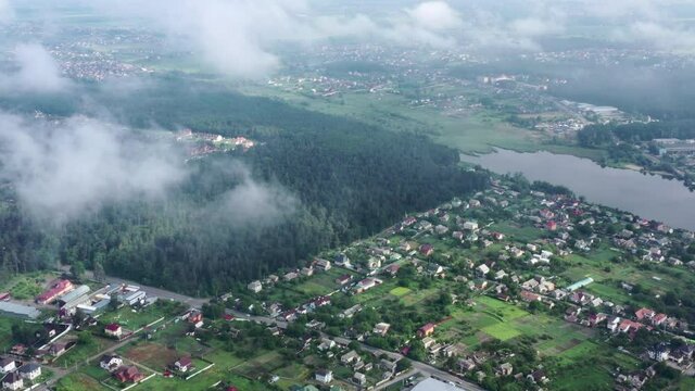 Orbitting Panorama of misty cumulus clouds over residential suburban cottages. Flight of the drone through the cinematic Dense misty clouds over the picturesque eco-friendly area of residential areas.