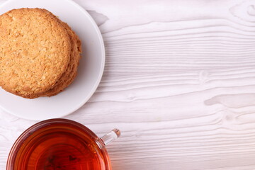 homemade cookies and a glass cup of black tea on the rustic white wooden background. close up