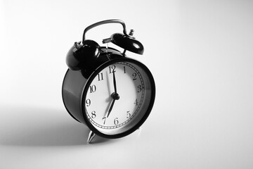 Black vintage alarm clock on table. White background. Wake up concept. An image of a retro clock...