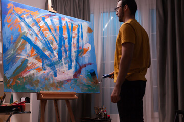 Innovative abstract painter using roller on canvas in art studio.