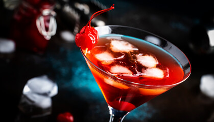 Manhattan alcoholic cocktail with bourbon, red vemuth, bitter, ice and cocktail cherry in glass, night mood image, copy space