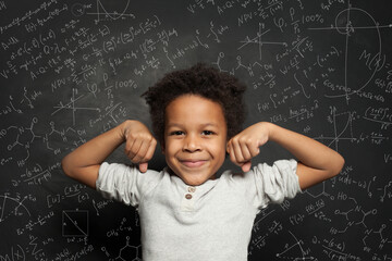 Cute black child student boy on chalkboard background with science formulas