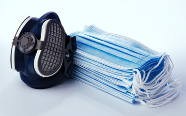 Stack of medical masks with respirator on white background