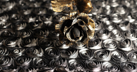 An iron rose on a shiny dark background. Bronze flower.