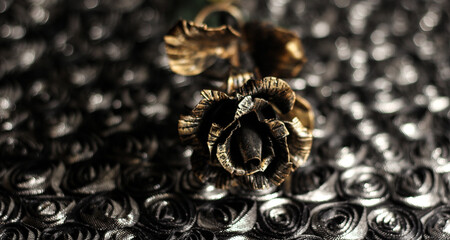 An iron rose on a shiny dark background. Bronze flower.