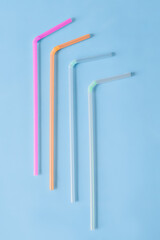 Multi-colored plastic tubules for drinks on a blue background.