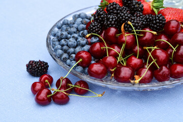 Berry fruits in a plate with strawberries, blueberries, cherries and blackberries. Summer mood.