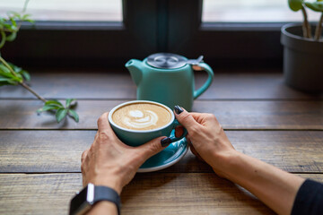 A cup of delicious strong coffee in female hands. Concept drinks, lifestyle, work, background.