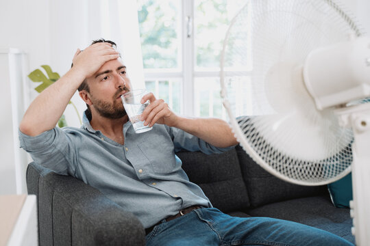 Man Refreshing With Electric Fan Against Summer Heat Wave