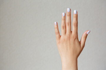 Gesture and sign, female hand showing stop on a light background. Empty space for text