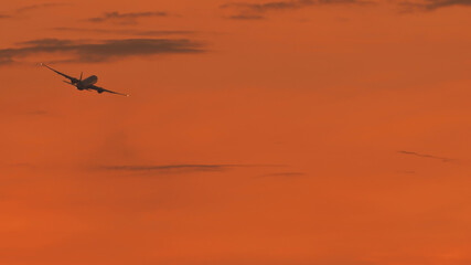 Naklejka na ściany i meble Take-off aircraft against the evening sky after sunset.