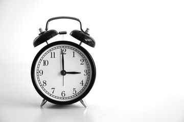 Black vintage alarm clock on table. White background. An image of a retro clock showing 03:00 pm/am.