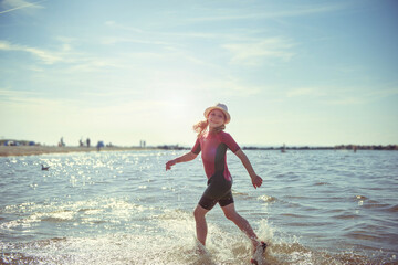 Happy pretty teen girl in neoprene swimingsuit  running in Baltic sea