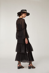 Fototapeta premium Fashion pretty woman beautiful makeup perfect body shape tan skin wear clothes summer collection organic black cotton cape, silk short dress stylish sandals shoes, accessory hat and jewelry earrings.