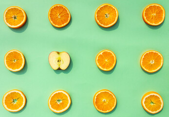 Bright, tasty, fresh, juicy orange slices with an apple slice on green background, natural vegan food, good for alphabet, vitamins for immune system