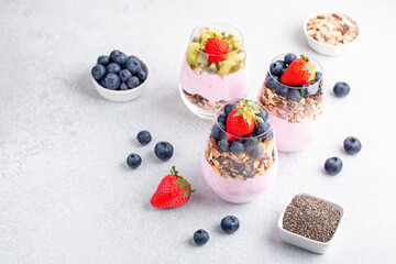 Chia seeds layered pudding with granola, blueberry and strawberry in glasses. Yogurt with chia seeds, berries, kiwi and muesli for healthy breakfast, copy space. Perfect for summer snack or dessert