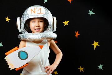 Portrait of a cute little Aisan girl, space at home, dreaming and playing astronaut. Funny family moments