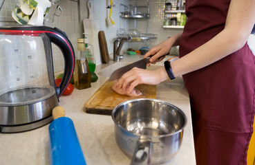 Cropped image of young lady standing in kitchen while cooking.