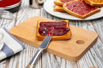 Crispy toasts covered with fruit jam served on kitchen table