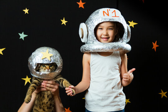 Portrait of a cute little Aisan girl with her cat, space at home, dreaming and playing astronaut. Funny family moments